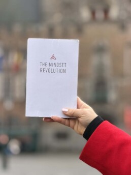 A hand holding up a copy of the book The Mindset Revolution