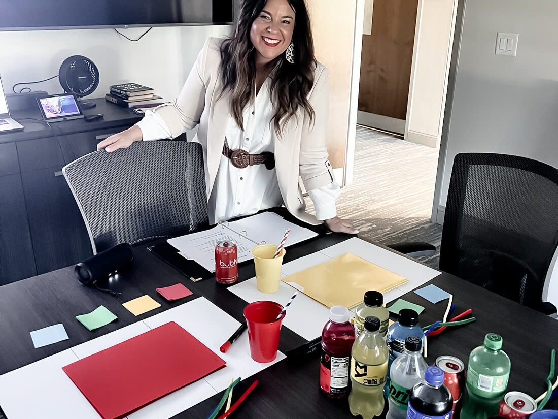 A boardroom table laid out for a Triad workshop with colour cards, notebooks and drinks