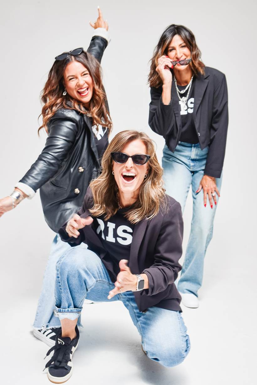 Studio portrait of the three founders, one kneeling in sunglasses and two standing behind