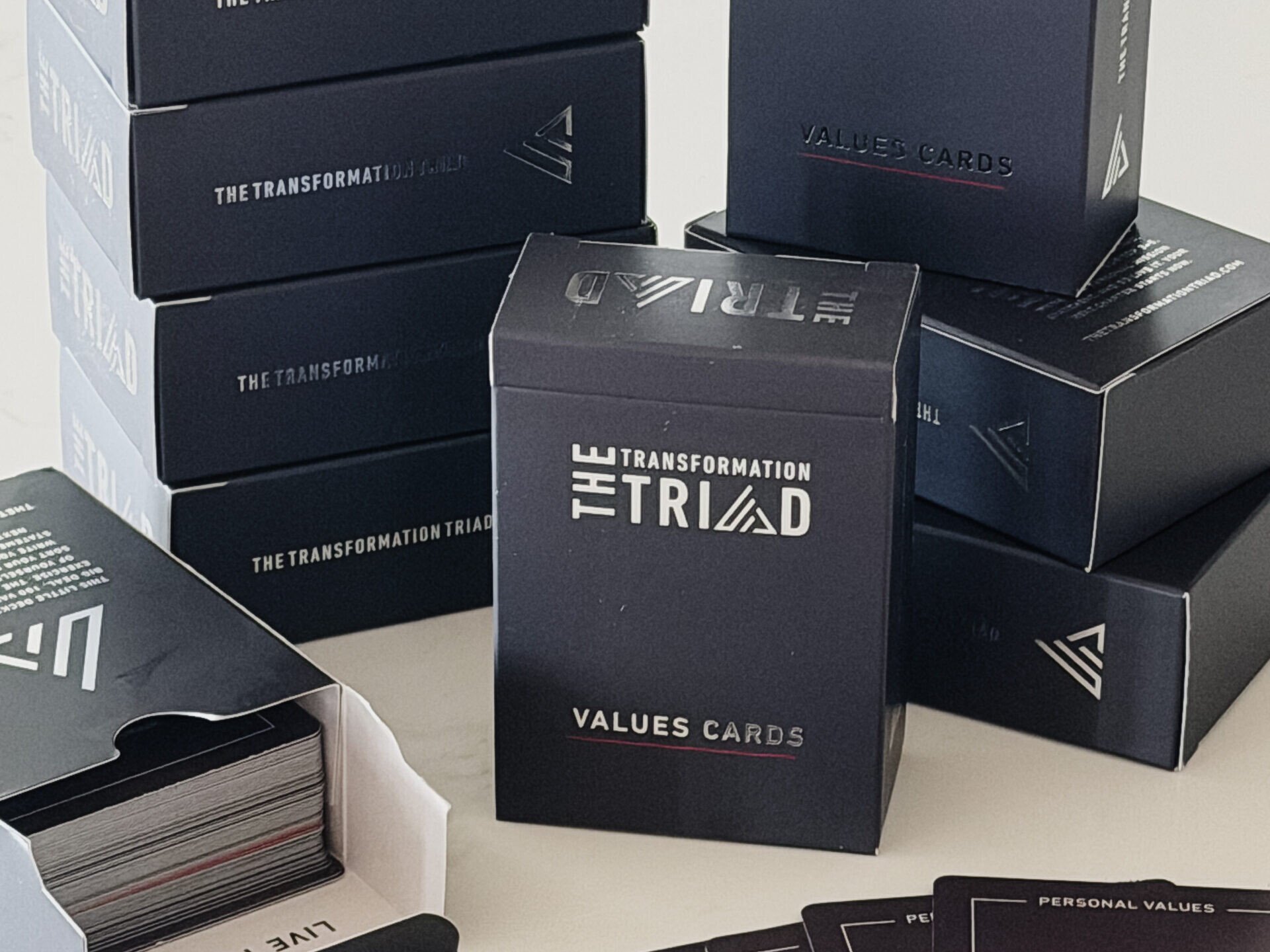 Stacked Transformation Triad Values Cards boxes with an open deck and cards fanned out